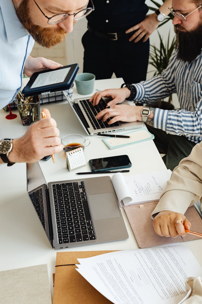 Teamwork in action with technology, papers, and collaboration at a dynamic office desk.